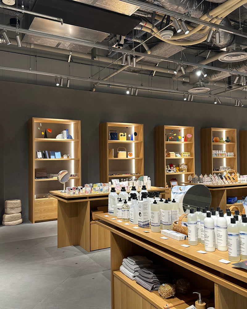 Interior view of a Japanese concept store featuring The Unscented Company sustainable home and personal care products displayed on minimalist wooden shelves.
