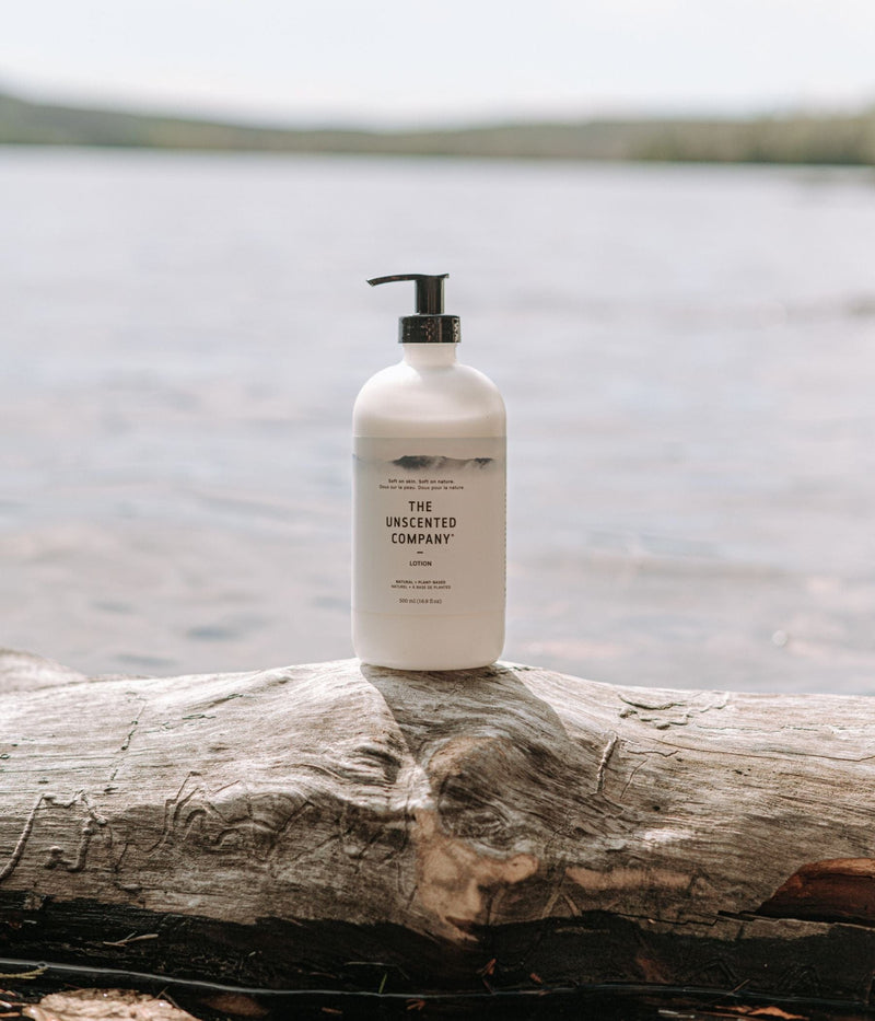 The 500ml Lotion in a plastic bottle on a tree branch with a lake in the background.