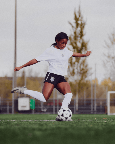 Soccer player kicking a ball on a field while wearing a The Unscented Company shirt, highlighting the brand’s connection to active lifestyles and community sports.
