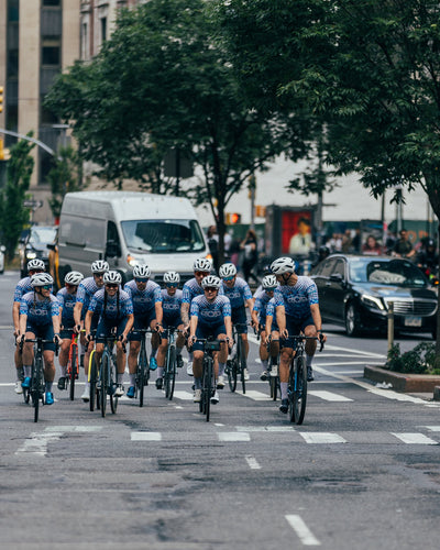 Group of cyclists riding together through New York City streets during a team ride, showcasing endurance cycling and an active lifestyle supported by The Unscented Company.
