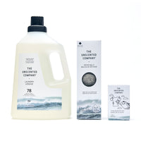 Un assortiment de produits The Unscented Company sur fond blanc comprenant une bouteille de lessive liquide de 1,95 L (78 brassées), une boîte de balles de séchage en laine et une boîte de barre détachante de 140 g.
