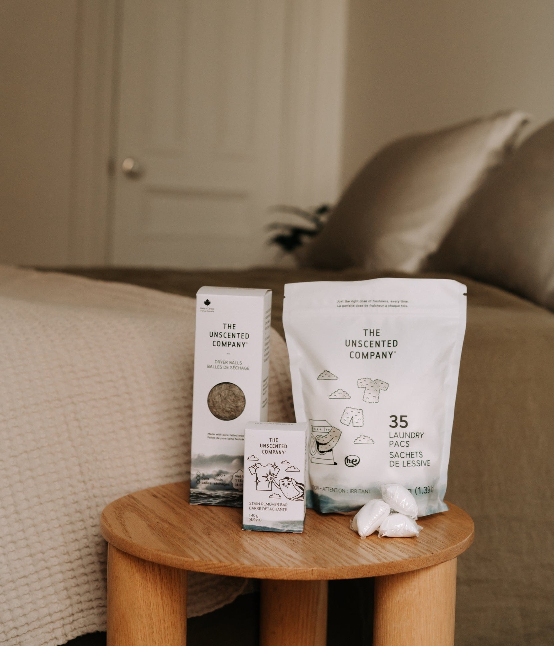 Un assortiment de produits sur une table en bois comprenant une boîte de balles de séchage, une barre détachante et un sac de 35 sachets de lessive avec trois sachets posés à côté.