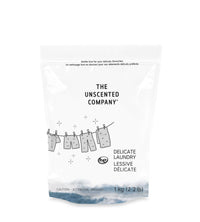 1 kg The Unscented Company delicate laundry detergent bag, featuring a clothesline illustration with garments hanging, set against a white background with a wave design at the bottom.
