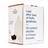 Side view of The Unscented Company 10 L laundry detergent box with dispenser tap, featuring the text “Load after load of fluffy goodness,” on minimalist white eco-friendly packaging.