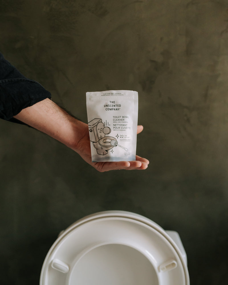 Hand holding The Unscented Company toilet bowl cleaner tablets, an eco-friendly and fragrance-free bathroom cleaning solution designed for powerful, sustainable cleaning.
