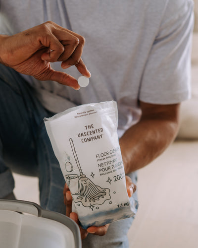 Person holding a floor cleaning tablet from The Unscented Company before adding it to water, showcasing an eco-friendly, fragrance-free solution for sustainable floor cleaning.
