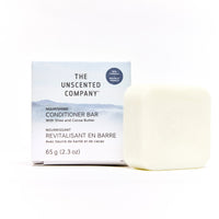 Le revitalisant nourrissant en barre de The Unscented Company au beurre de karité et de cacao, présenté à côté de sa boîte, mettant en valeur sa texture lisse et son emballage épuré.