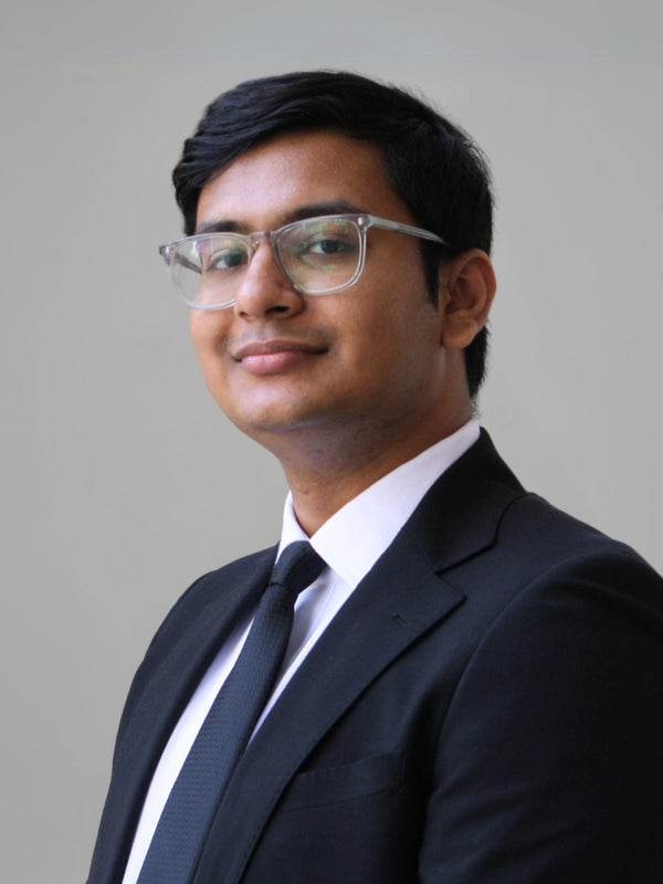 Man wearing glasses and a suit against a plain background